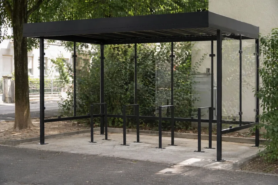 Abri vélo Vitria à parois vitrées installé en pied d'immeuble, arceaux au sol