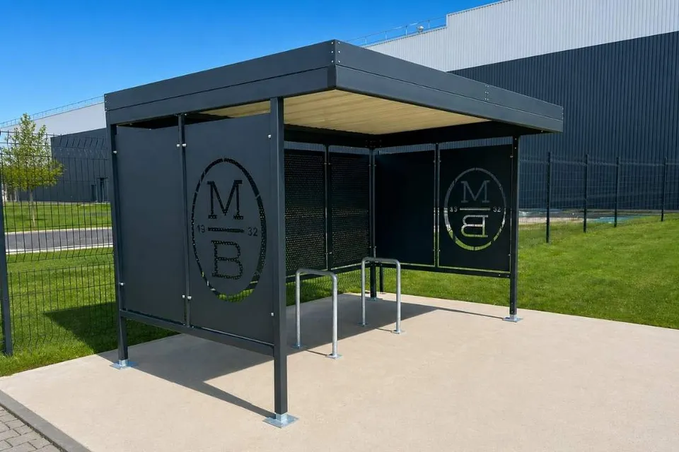 Abri vélo Fortis gris anthracite à faces en tôle pleine découpée au laser au logo du client, avec arceaux galvanisés