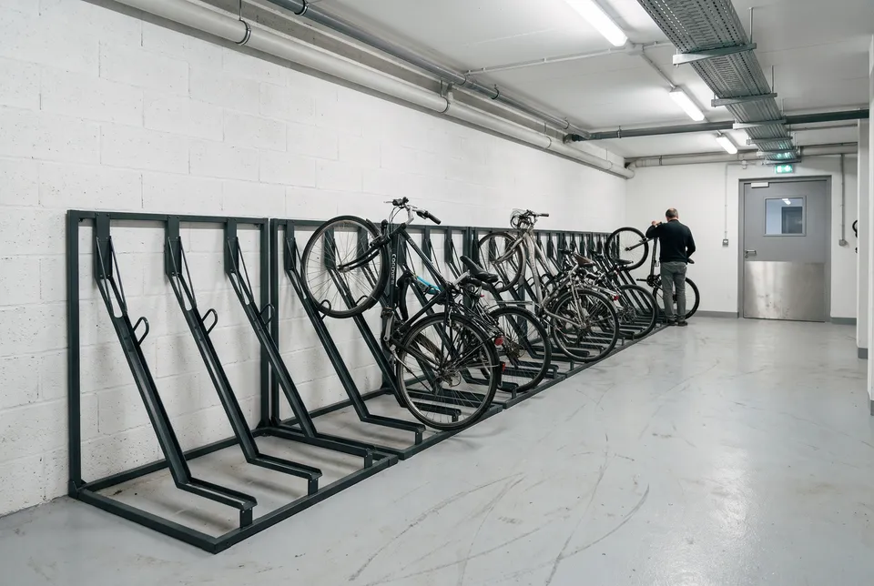 Racks vélo Inclinéo en acier anthracite alignés le long du mur d'un local vélo, vélos accrochés en position inclinée